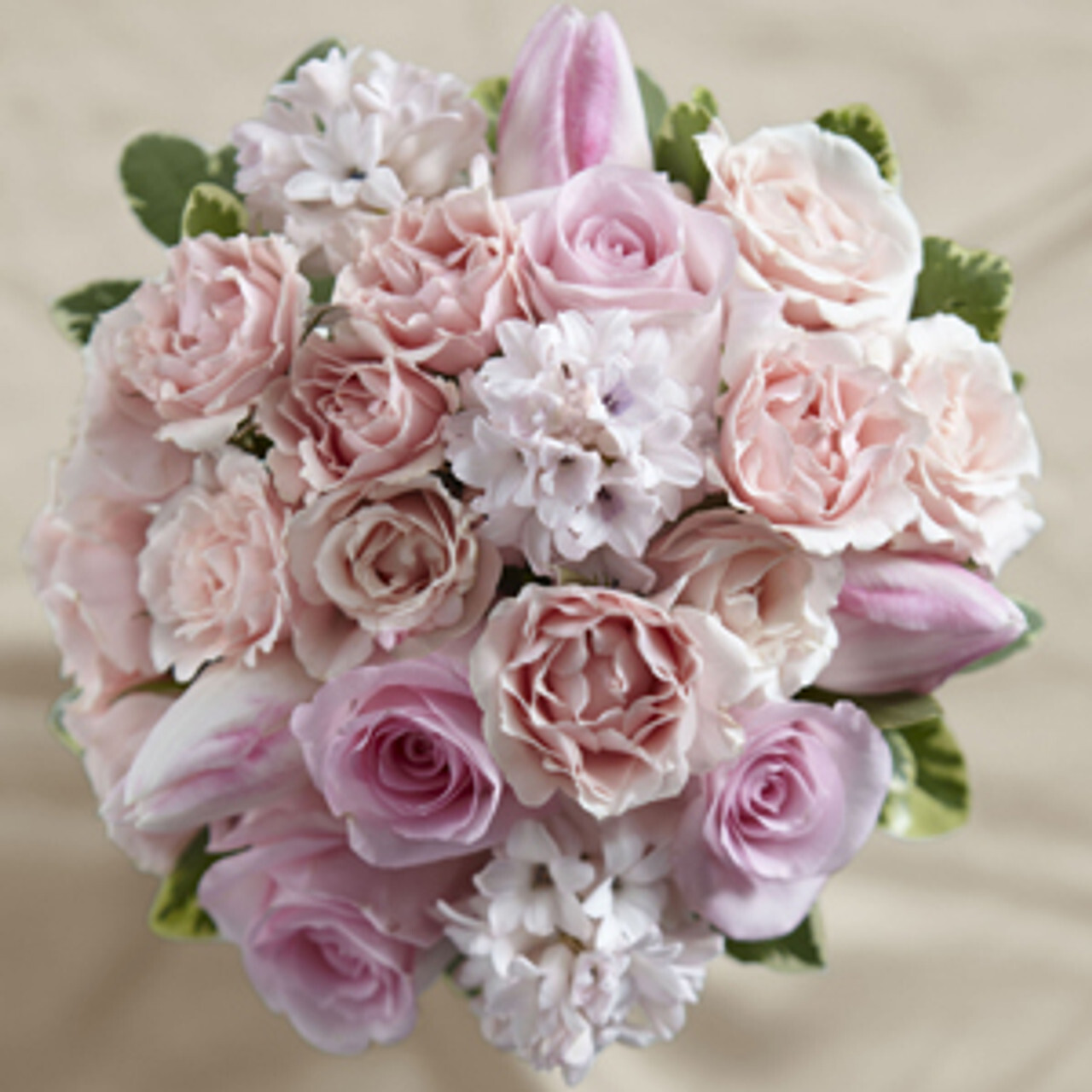 Elegant pastel pink and white floral arrangement featuring roses, tulips, and delicate blossoms, set against a neutral background.