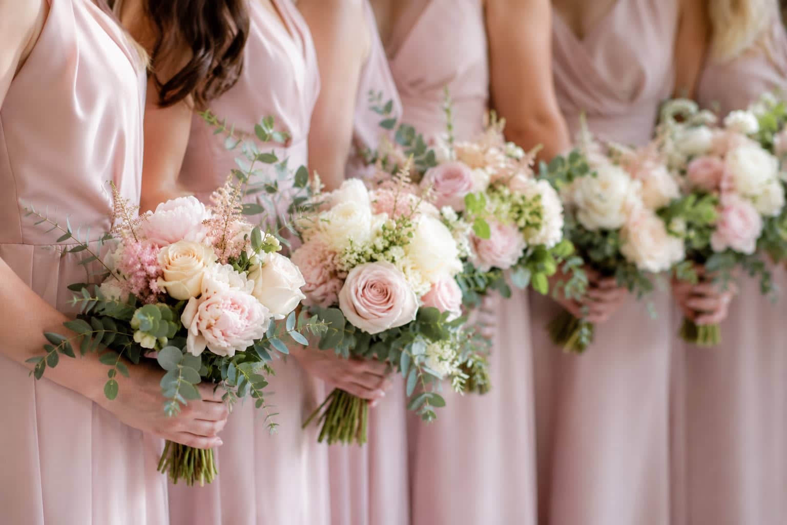 Bridesmaid wearing pink dress holding a bridesmaids flowers designs