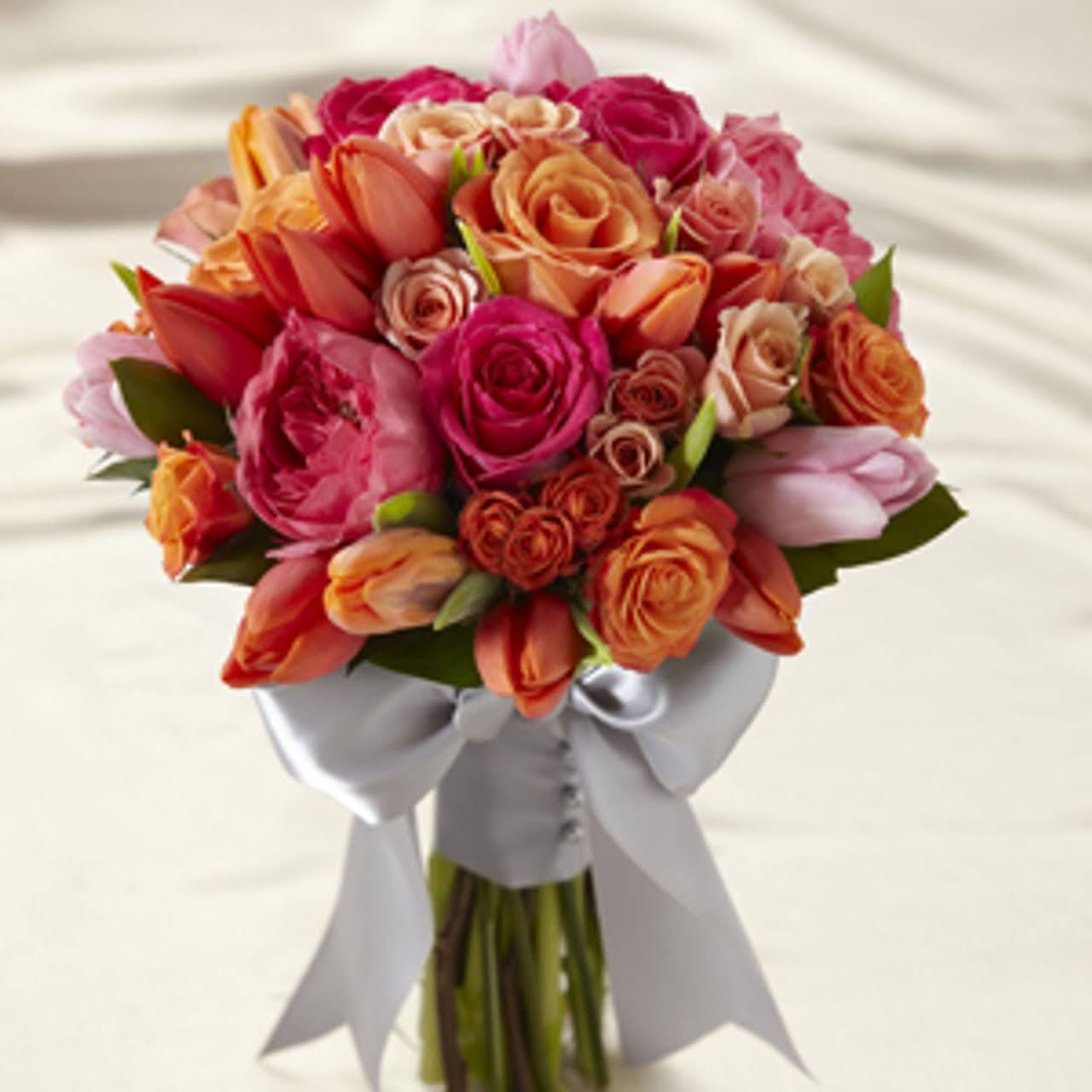 Colorful bouquet of roses and tulips in shades of red, orange, and pink, tied with a white satin ribbon.