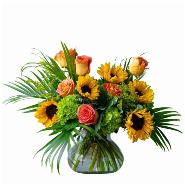 Bright sunflower and rose centerpiece with lime hydrangea and tropical greenery in a rounded glass vase.
