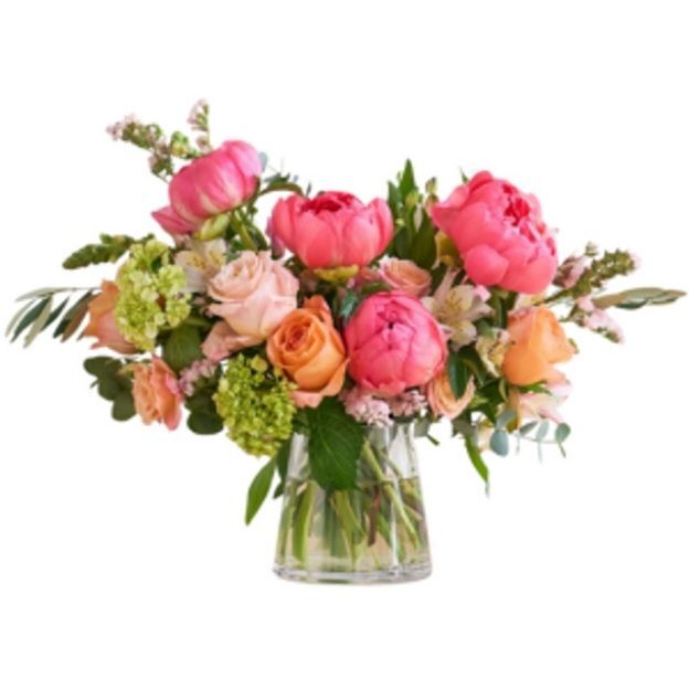 Colorful bouquet of pink, peach, and green flowers arranged in a clear vase with lush green foliage.