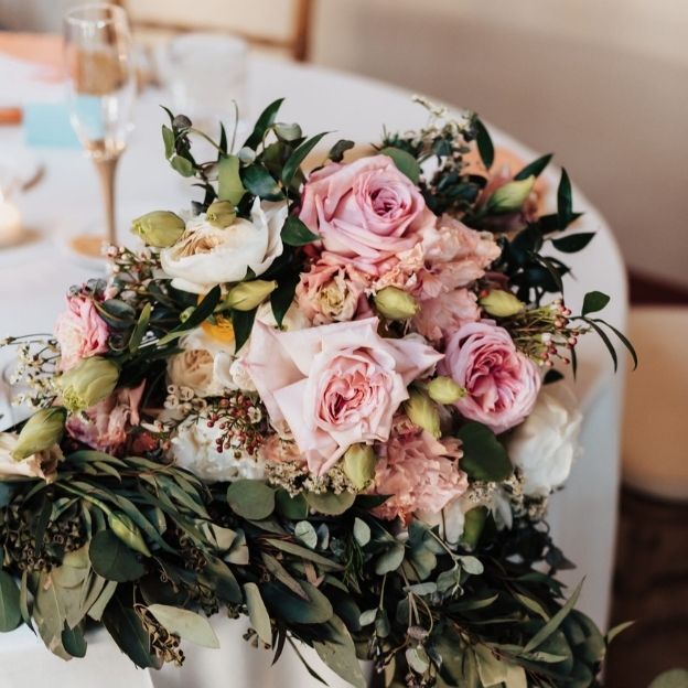 Elegant wedding bouquet with pink and white roses, greenery, and buds on a white tablecloth.