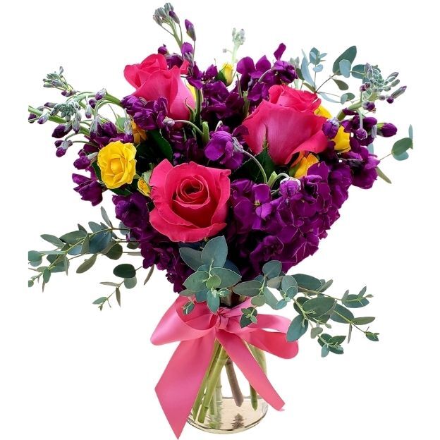 Vibrant bouquet of fuchsia roses, deep purple blooms, yellow accents, and eucalyptus in a vase with a pink bow.