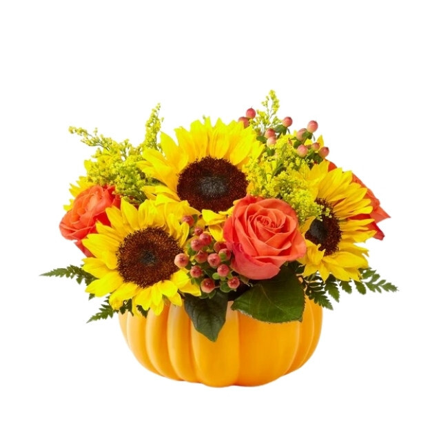 Autumn arrangement of bright sunflowers and orange roses with yellow filler flowers in a pumpkin-shaped container.