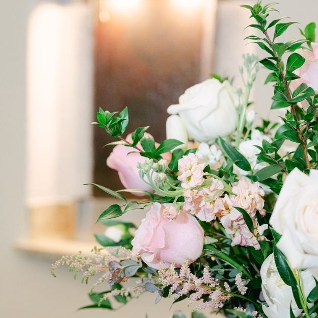 Pastel bouquet detail with white and blush roses, astilbe, eucalyptus, and fresh greens in soft focus.